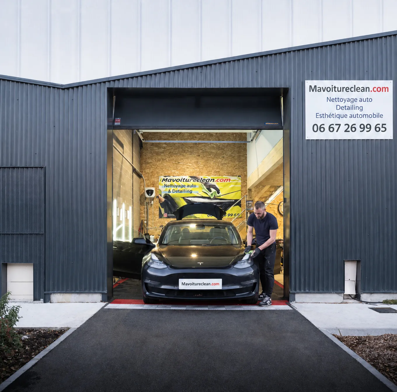 La porte ouverte de l'atelier Mavoitureclean.com à Mérignac, une Tesla en cours de nettoyage