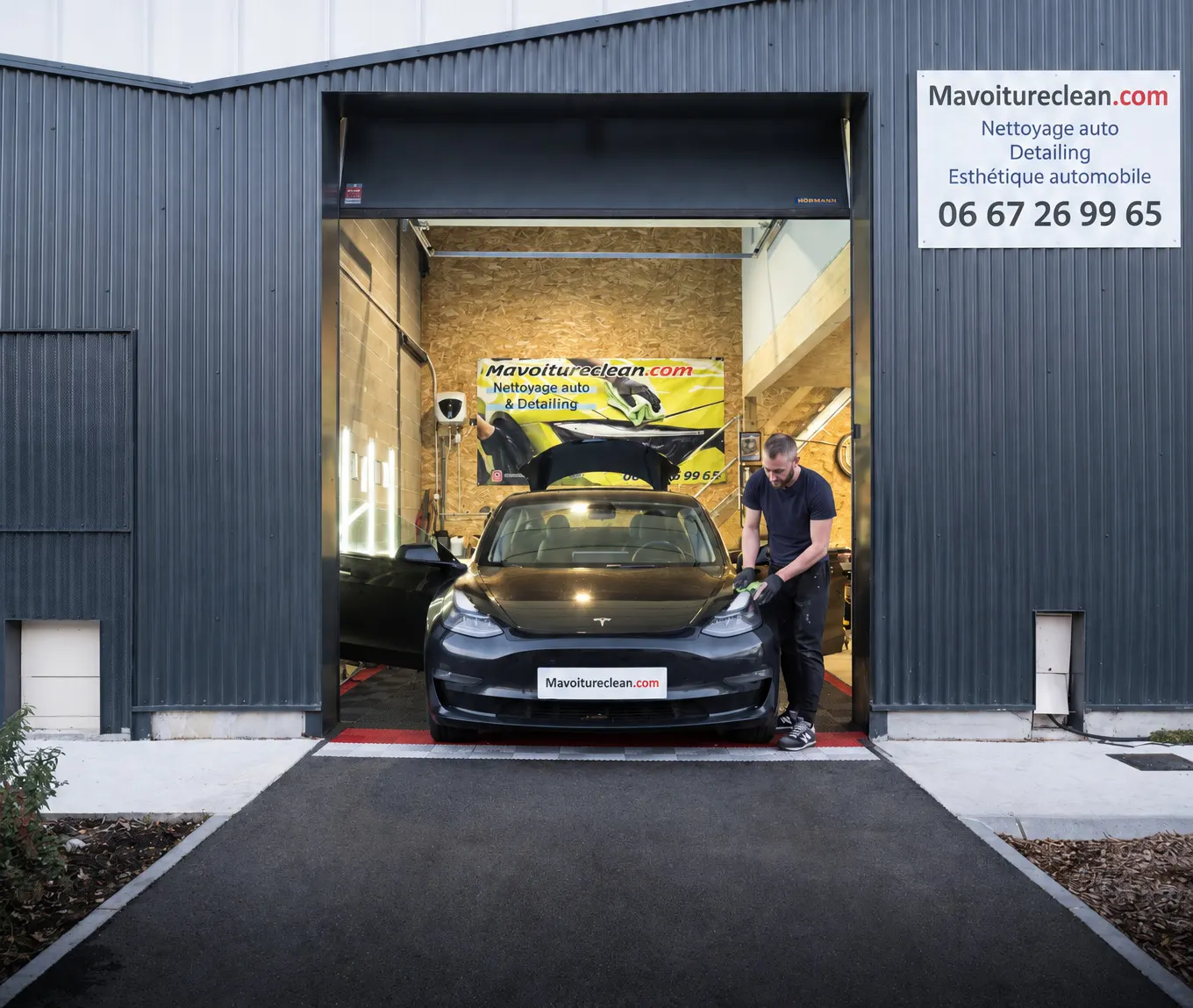 La porte ouverte de l'atelier Mavoitureclean.com à Mérignac, une Tesla en cours de nettoyage