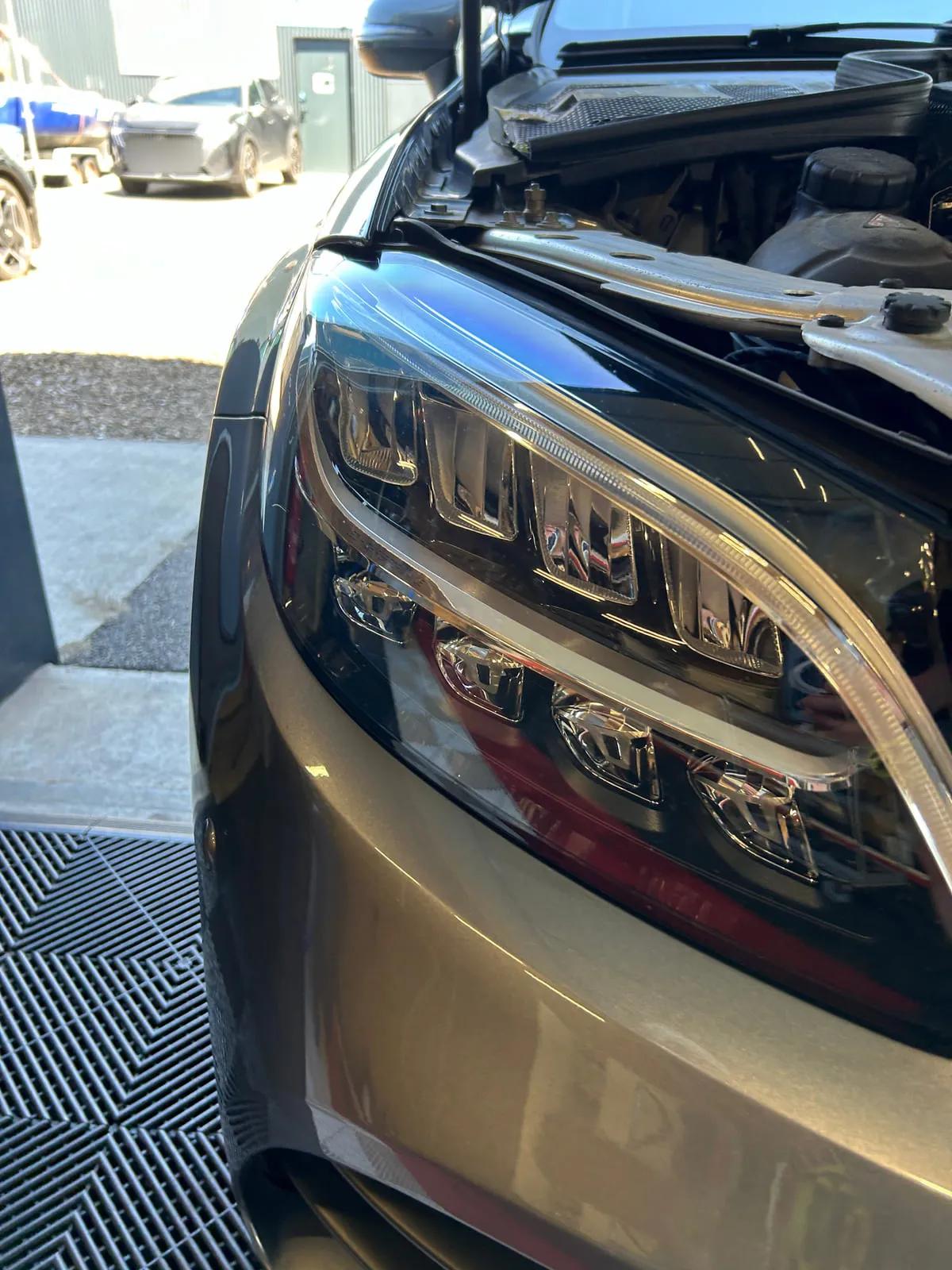 Phare à LED d'une Mercedes grise en gros plan, optique transparente, capot ouvert